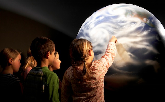 Un grup de nens i nenes mira una imatge de la Terra Un grup de nens i nenes mira una imatge de la Terra