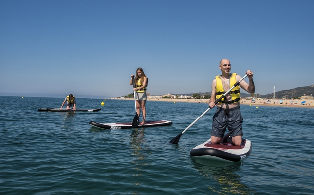 Una família fent paddle surf a la platja de les Dunes de Santa Susanna Una família fent paddle surf a la platja de les Dunes de Santa Susanna