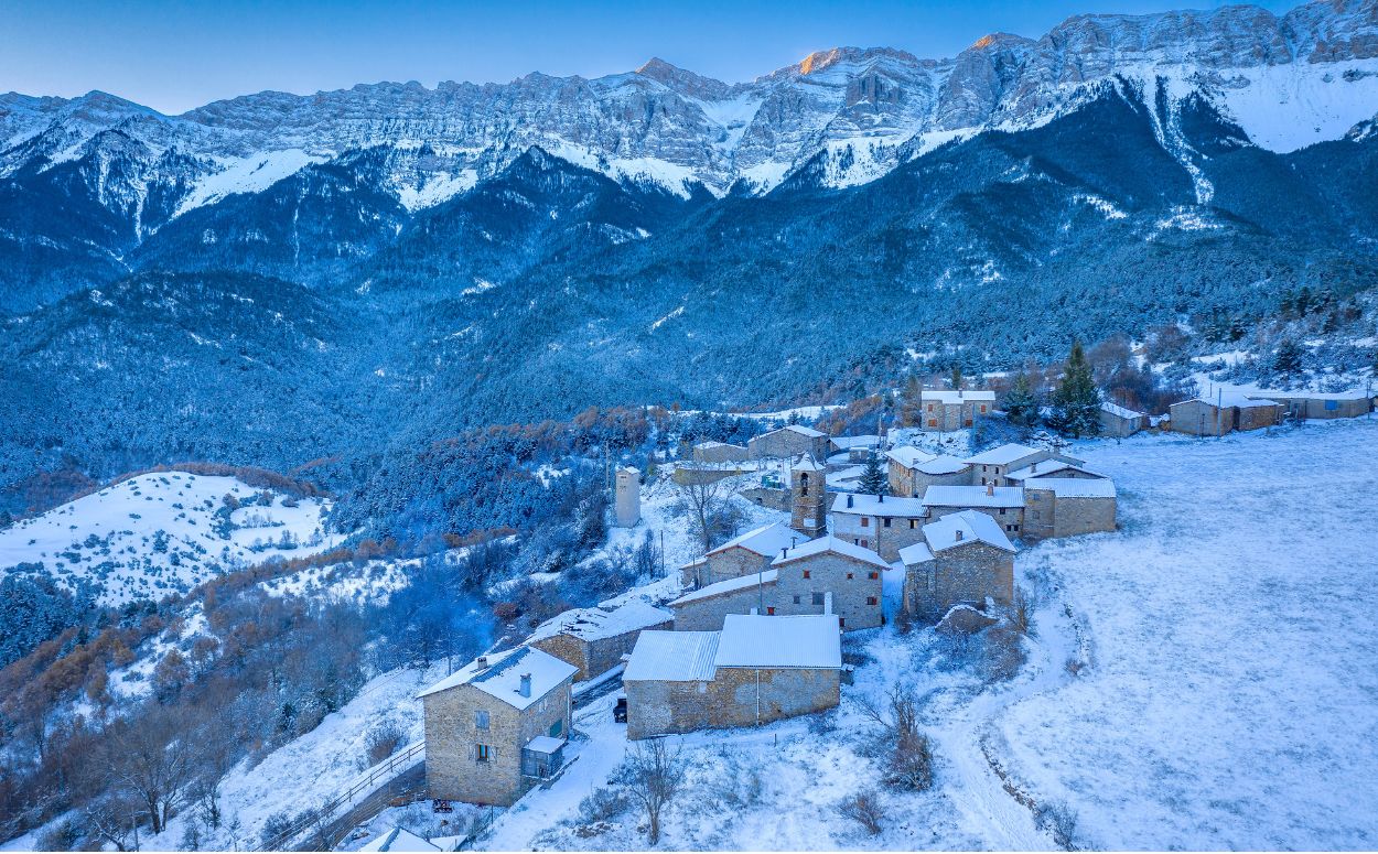 El petit poble d’Estana es lleva emblanquinat amb la serra del Cadí al fons El petit poble d’Estana es lleva emblanquinat amb la serra del Cadí al fons