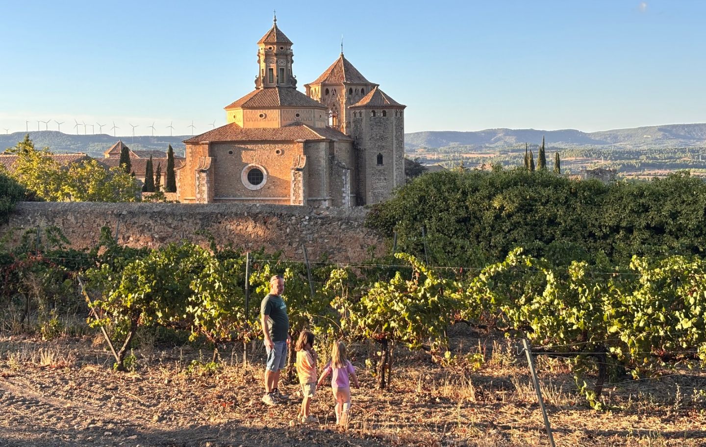 La família passeja per les vinyes del costat del monestir de Poblet, al fons